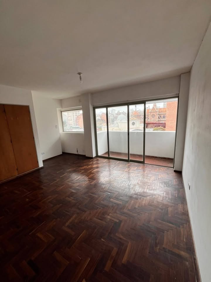 Ambiente principal con piso de parqué y salida al balcón en Independencia 640